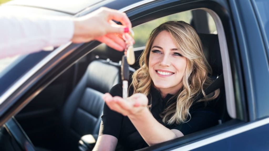 A woman sitting in the driver's seat of a car receives a set of keys from another person outside the vehicle, ready to start driving in Costa Rica.